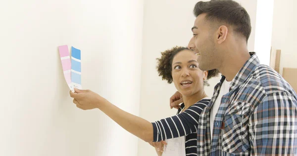 Casal jovem tentando escolher uma cor de pintura — Fotografia de Stock