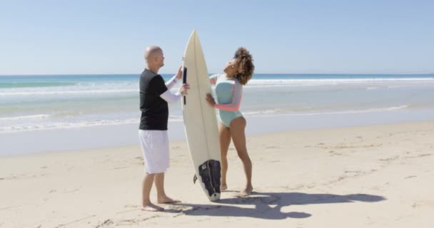 समुद्र तट पर सर्फबोर्ड के साथ पुरुष और महिला — स्टॉक वीडियो