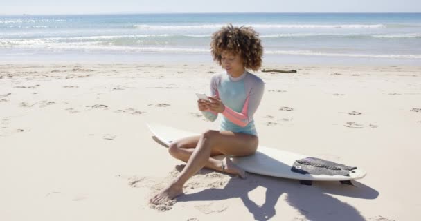 Mujer sentada en la playa usando smartphone — Vídeos de Stock