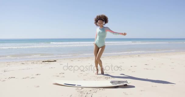 Жінка слухає музику і танцює на пляжі — стокове відео