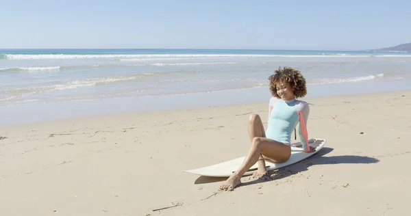 Mujer joven sentada en una tabla de surf — Foto de Stock