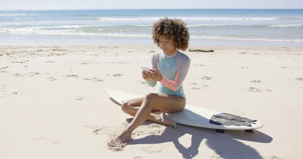 Feminino sentado na praia usando smartphone — Fotografia de Stock