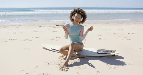 Vrouwelijke luisteren muziek op strand — Stockfoto