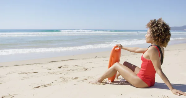 Feminino com flutuador de resgate sentado na praia — Fotografia de Stock