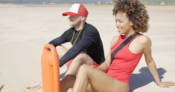 Salvavidas sonrientes sentados en la playa — Foto de Stock