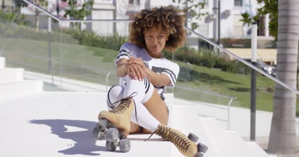 Femme souriante assise dans les escaliers portant des patins à roulettes — Video