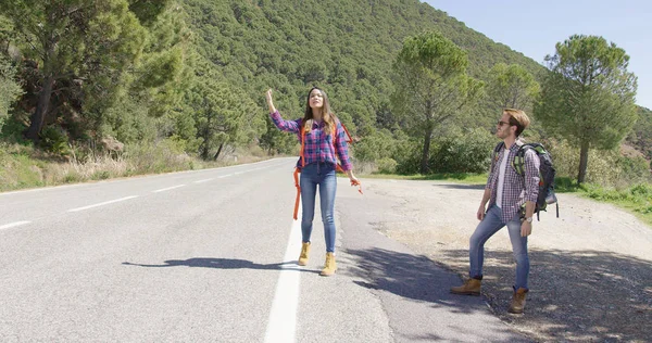 Jóvenes viajeros enganchan senderismo en carretera —  Fotos de Stock