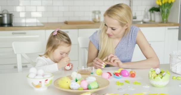 Mother looking at girl coloring eggs — Stock Video