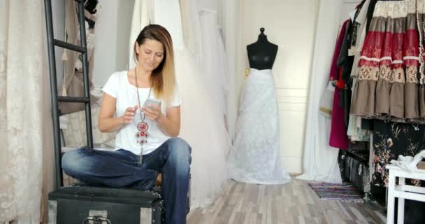 Vrouw in kleermakers winkel met telefoon — Stockvideo