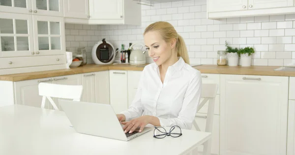 Giovane donna che utilizza il computer portatile in cucina — Foto Stock