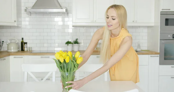 Woman arranging vase with flowers on table — Stock Photo, Image