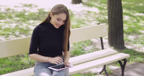 Весела молода жінка використовує планшет зовні — стокове відео