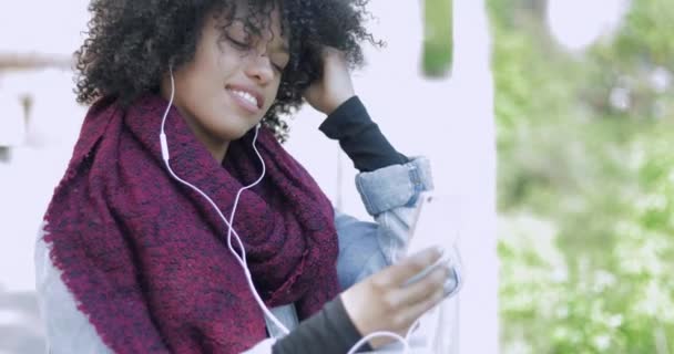 Afrikaanse vrouw met hoofdtelefoon en de telefoon poseren — Stockvideo