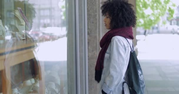 Νεαρή γυναίκα ψάχνει στο παράθυρο του καταστήματος — Αρχείο Βίντεο