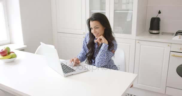 Mulher sorridente usando laptop na cozinha — Vídeo de Stock