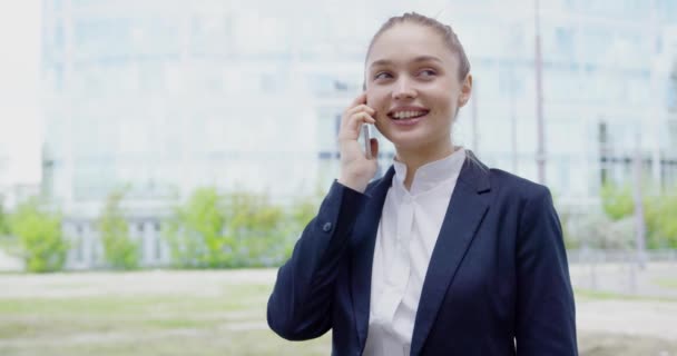 Веселая девушка разговаривает по телефону на улице — стоковое видео