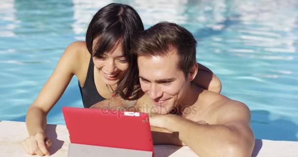 Smiling couple in swimming pool use digital device — Stock Video