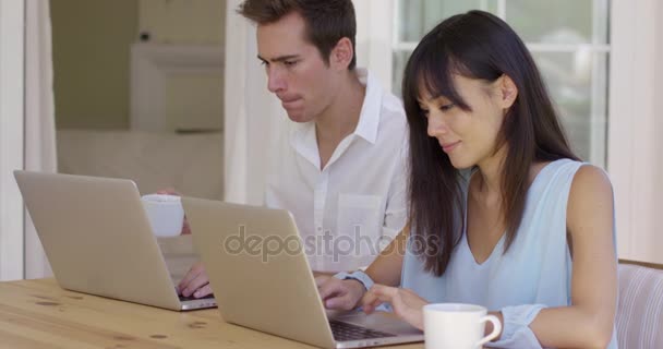Klidný mladý pár sedí u stolu pomocí přenosného počítače — Stock video