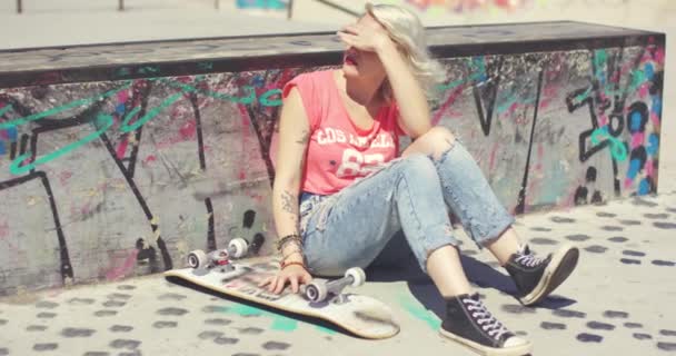 Ung kvinna väntar en vän på en skateboardpark — Stockvideo