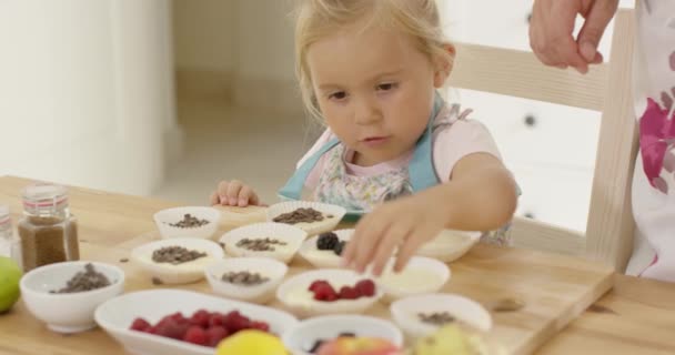 Kleines Mädchen greift nach Beeren auf Muffins — Stockvideo