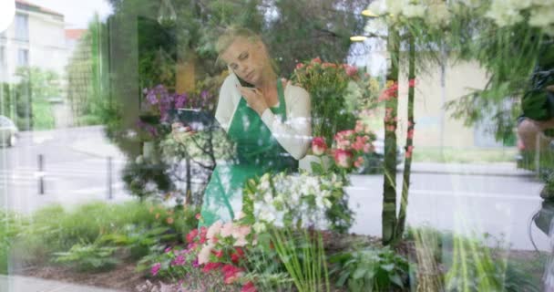 Mujer en floristería hablando de teléfono — Vídeos de Stock