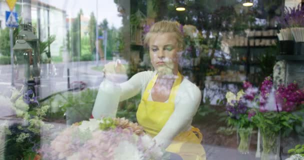 Vrouw beregening bloemen in de winkel — Stockvideo