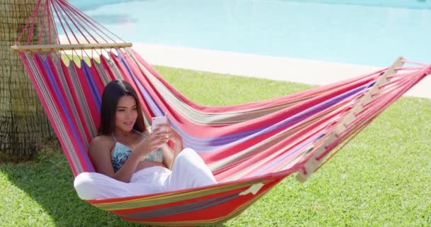 Woman laying down in hammock while using phone — Stock Video