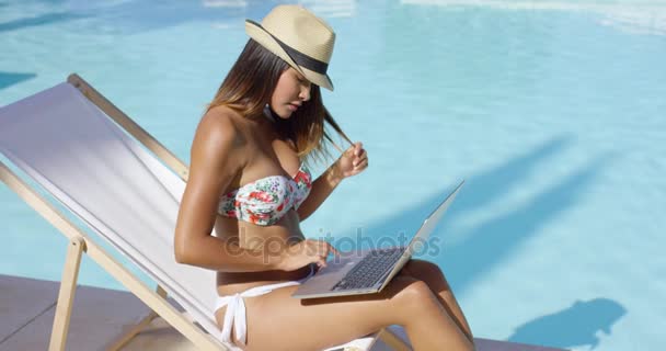 Mujer joven de moda usando un ordenador portátil en la piscina — Vídeo de stock