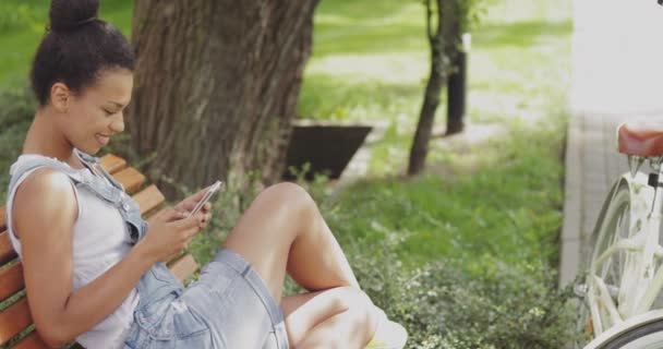 Content girl using smartphone in park — Stock Video