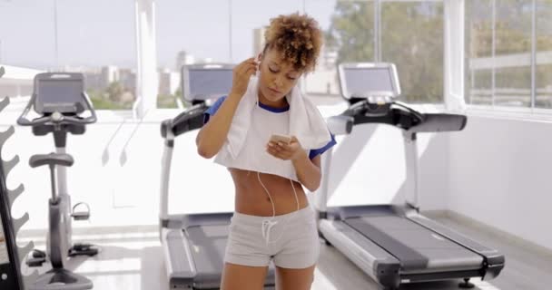 Дівчина з телефоном у спортзалі — стокове відео