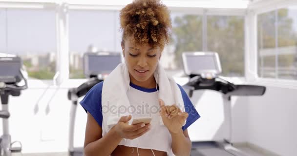 Чарівна дівчина використовує телефон у спортзалі — стокове відео