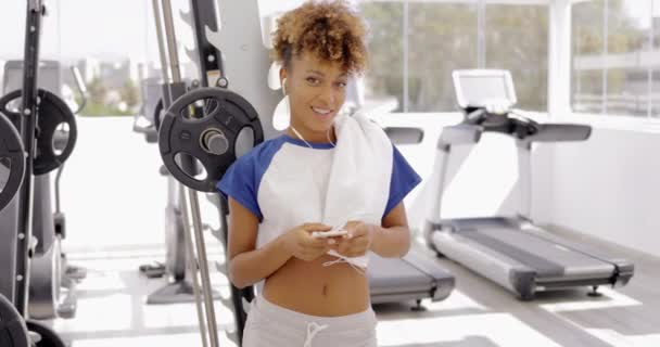 Smiling model posing with phone in gym — Stock Video
