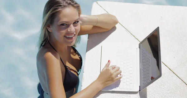 Mujer sonriente relajándose en la piscina con portátil —  Fotos de Stock