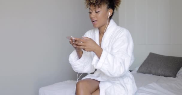 Красивая девушка с помощью смартфона на кровати — стоковое видео