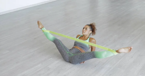 Woman stretching legs with band — Stock Photo, Image