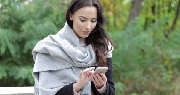 Femme utilisant un smartphone dans le parc — Video