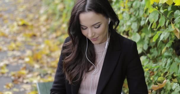 Жінка слухає музику в парку — стокове відео