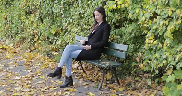 Woman listening to music on park bench — Stock Video