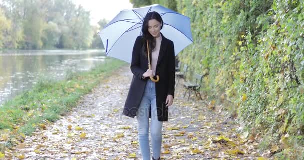 Frau mit Regenschirm läuft in Teichnähe — Stockvideo