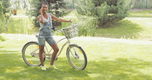 Giovane ciclista parlando telefono nel parco — Foto Stock