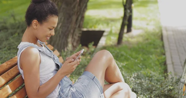 Chica de contenido usando smartphone en el parque — Foto de Stock