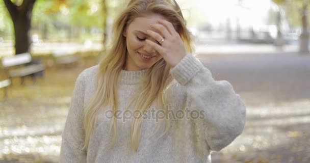 Donna sorridente che liscia capelli in parco — Video Stock