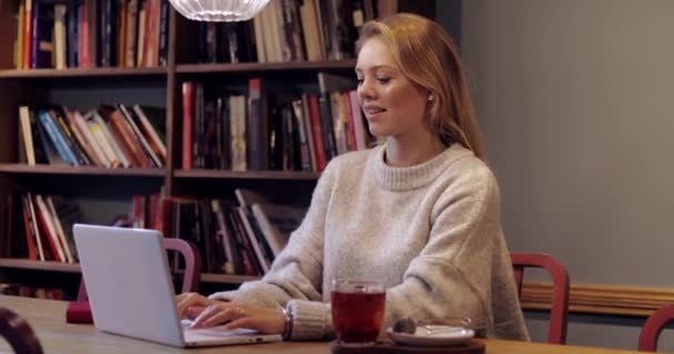 Mujer sonriente usando portátil en la biblioteca — Vídeos de Stock