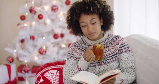 Frau liest ein Buch vor einem Weihnachtsbaum — Stockvideo