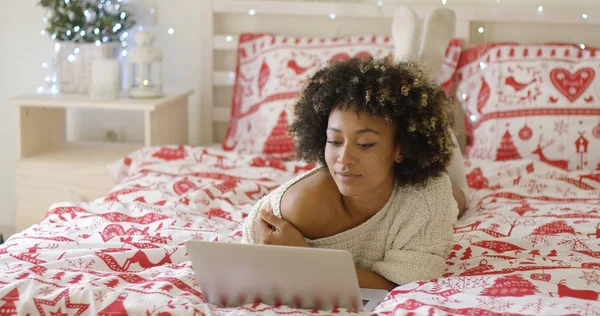 Όμορφη γυναίκα διαβάζει κάτι για το laptop στο κρεβάτι — Φωτογραφία Αρχείου