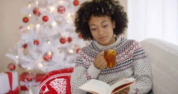 Kvinna läser en bok framför en julgran — Stockfoto