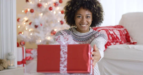 Lachende vriendelijke vrouw biedt een gift van Kerstmis — Stockfoto