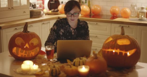 Frau mit Laptop inmitten von Halloween-Dekorationen — Stockvideo
