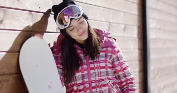 Mujer con snowboard cerca de la pared de madera — Vídeo de stock