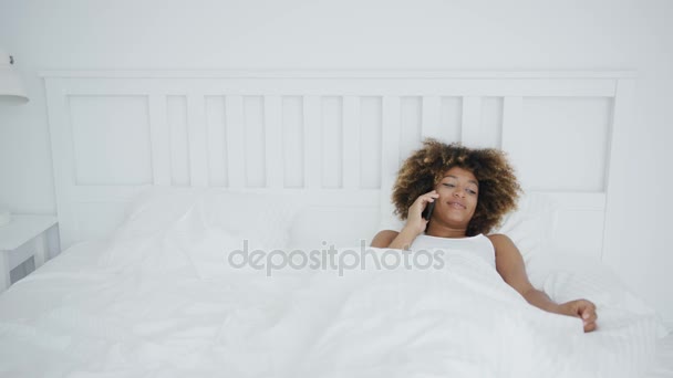 Mujer sonriente en la cama teniendo llamada telefónica — Vídeos de Stock